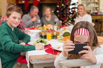 Little girl holding smartphone during christmas dinner