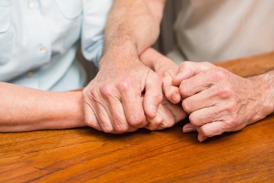 Senior Couple Holding Hands On Table