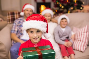 Smiling son holding gift in front of his family