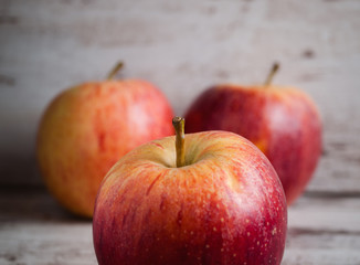 Three red apples over wooden background
