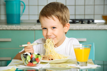 laughing boy eating spaghetti and holding the fork