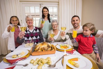 Obraz na płótnie Canvas Smiling family toasting to camera during christmas dinner