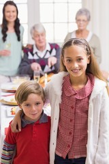 Brother and sister smiling at camera in front of their family