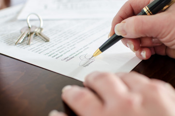 Woman signing a real estate contract - obrazy, fototapety, plakaty