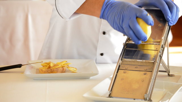 Professional chef hands cutting potatoes with mandolin