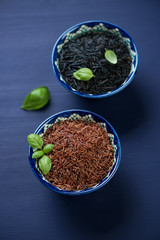 Ceramic pialats with red and black raw rice kernels, close-up