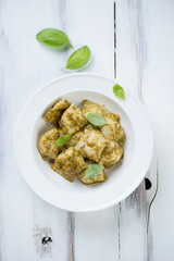 Ravioli with basil pesto in a glass plate, view from above