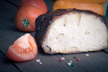 piece of pork, peppers and tomatoes on an old wooden table. Tint