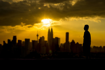 Fototapeta na wymiar Silhouette of a man looking at the city from distance