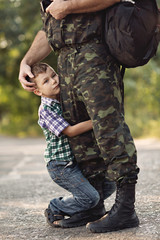 boy and soldier in a military uniform say goodbye before