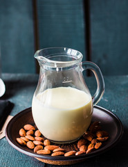 condensed milk in a jug glass, dark almonds on a plate