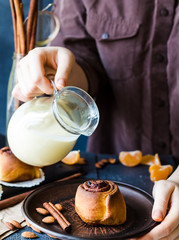 Cinnabon cinnamon rolls with cream sauce to pour, hands