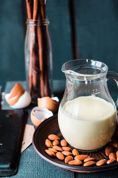 condensed milk in a jug glass, dark almonds on a plate