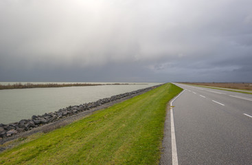 Road on a dike along a lake in autumn