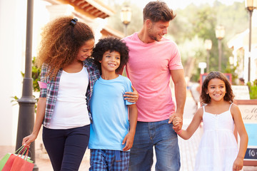 Family Walking Along Street With Shopping Bags