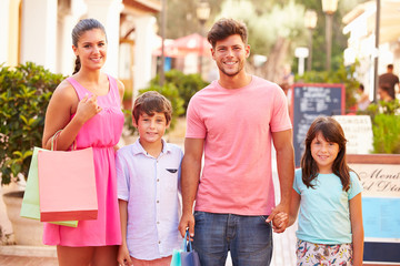 Portrait Of Family Walking Along Street With Shopping Bags