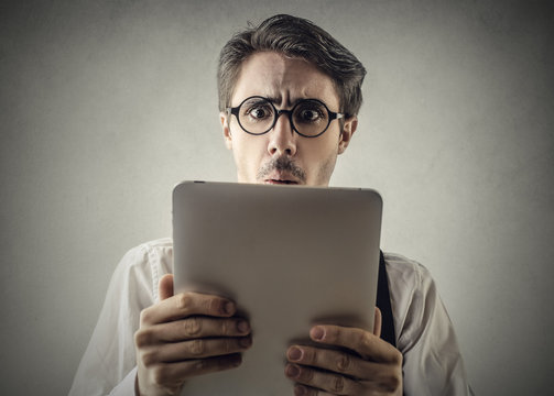 Surprised man reading something on a tablet