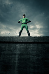 Confident superhero standing on a wall © stokkete