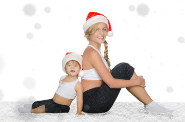 family sits in snow in Santa hats