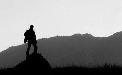 Black and white silhouette of hiker on the top of the hill