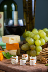 selection of soft cheese with fruits, spices and meat on board