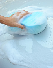 female hand is cleaning  car bonnet with blue sponge