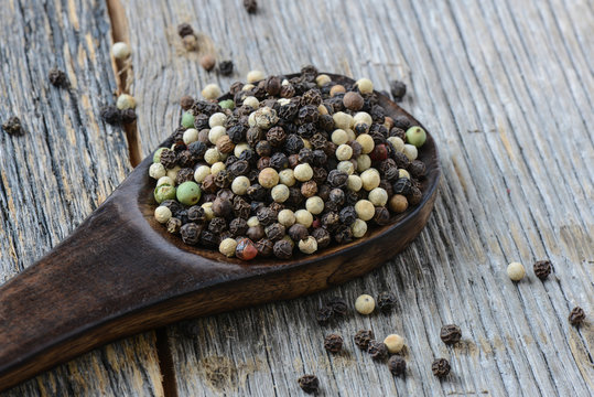 black ,white, green, brown peppercorns on rustic wooden table