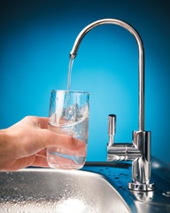 hand pouring a glass of water from filter tap