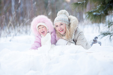 Happy mother and kid lying in snow outdoor