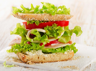 Sandwich with turkey and fresh vegetables on  wooden background