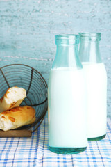 Retro bottles of tasty milk and bread, on table