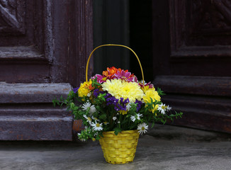 Flowers in basket on wooden door background