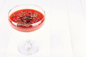 Tomato juice in glass goblet on light wooden background