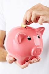 Handsome young man with piggy bank isolated on white