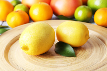 Ripe citrus with green leaves on plate close-up