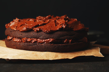 Chocolate cake with chocolate cream on wooden table close-up