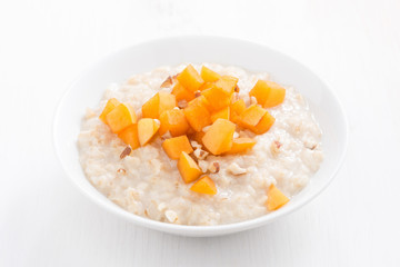 oatmeal with fresh apricots and nuts on a white wooden table