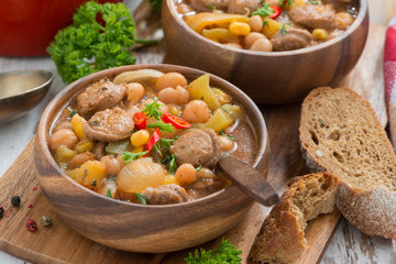 vegetable stew with sausages in a wooden bowl on board and bread