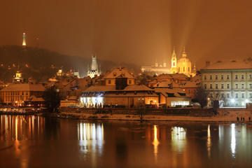 Fototapeta na wymiar Night snowy Prague Bridge Tower and St. Nicholas' Cathedral