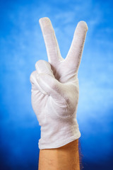 Hand in white glove showing victory sign