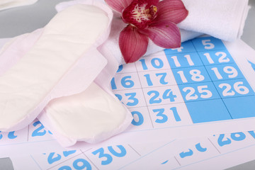 Sanitary pads and lilac orchid on blue calendar background