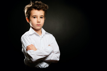 Little boy portrait in low key with arms crossed