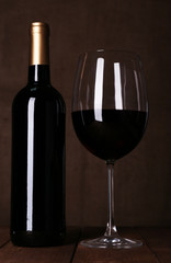 Red wine glass and bottle of wine on dark background