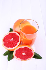 Grapefruit juice and fresh grapefruit on wooden table