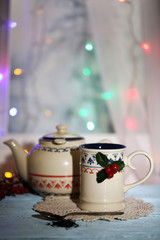 Christmas composition with cup and teapot of hot drink,