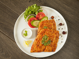 Grilled fish tikka served on a plate with salad and tarter sauce