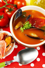 Tasty soup with shrimps, mussels, tomatoes and black olives in
