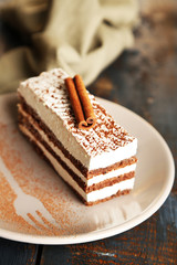 Tasty tiramisu cake on plate, on wooden table