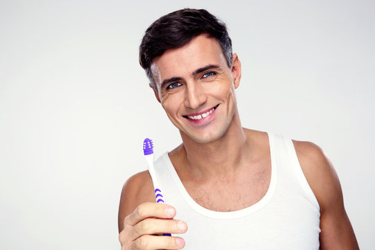 Happy Man Holding Toothbrush On Gray Background