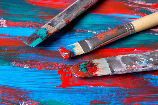 brushes on acrylic paint background with blue and red strokes